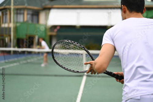 Man tennis player standing in ready position to receive a serve, practicing for competition on a court