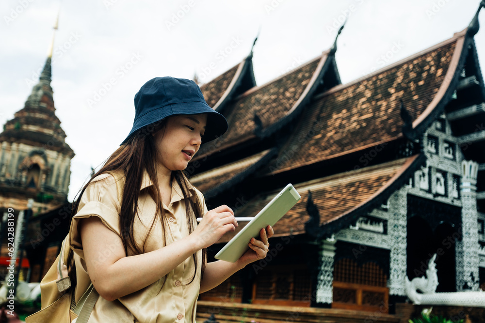 Asian traveller woman with tablet at ok moli temple in Chiang Mai province, Thailand