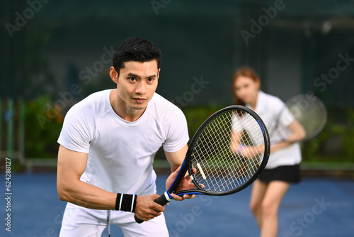 Two focused tennis player standing in ready position to receive a serve, practicing for competition on a court