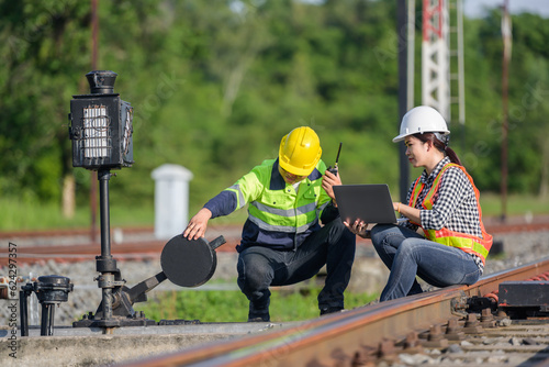 A railway worker or engineer is maintaining a railway track using a laptop computer checking the construction process of a railway switchgear and checking the work in a railway station.