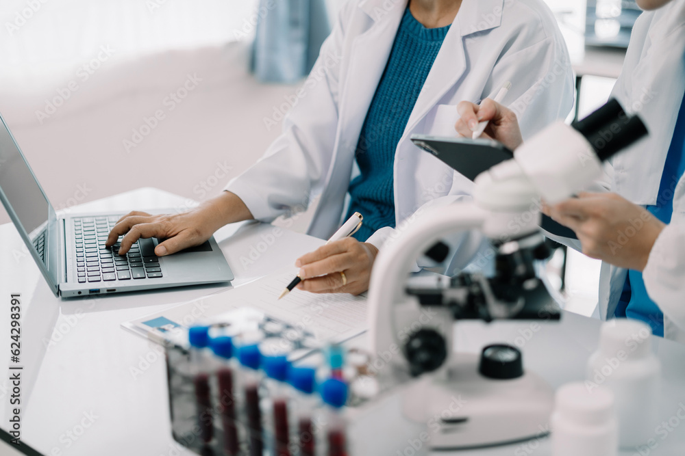 Medical Research Laboratory: Two scientists working, using digital tablets and laptop, analyzing samples, talking, developing biotechnology. Medical Research Laboratory: Two scientists working, using digital tablets and laptop, analyzing samples, talking, developing biotechnology.