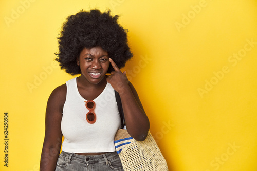 Beach-ready African-American woman, summer vacation vibe showing a disappointment gesture with forefinger. © Asier