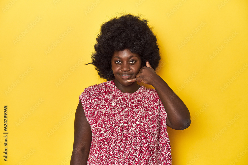 African-American woman with afro, studio yellow background showing a mobile phone call gesture with fingers. African-American woman with afro, studio yellow background showing a mobile phone call gesture with fingers.