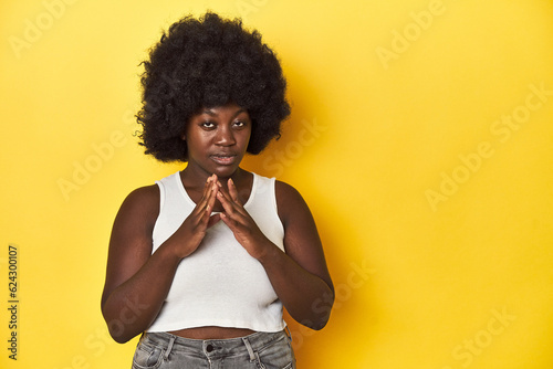 African-American woman with afro, studio yellow background making up plan in mind, setting up an idea.