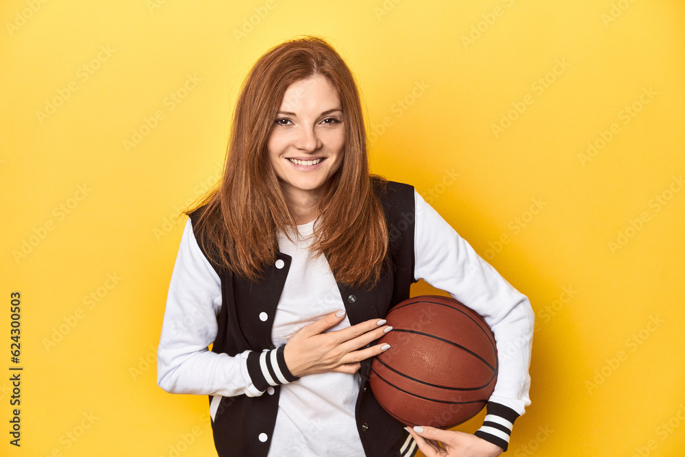 Sporty redhead with baseball jacket and basketball laughing and having fun.