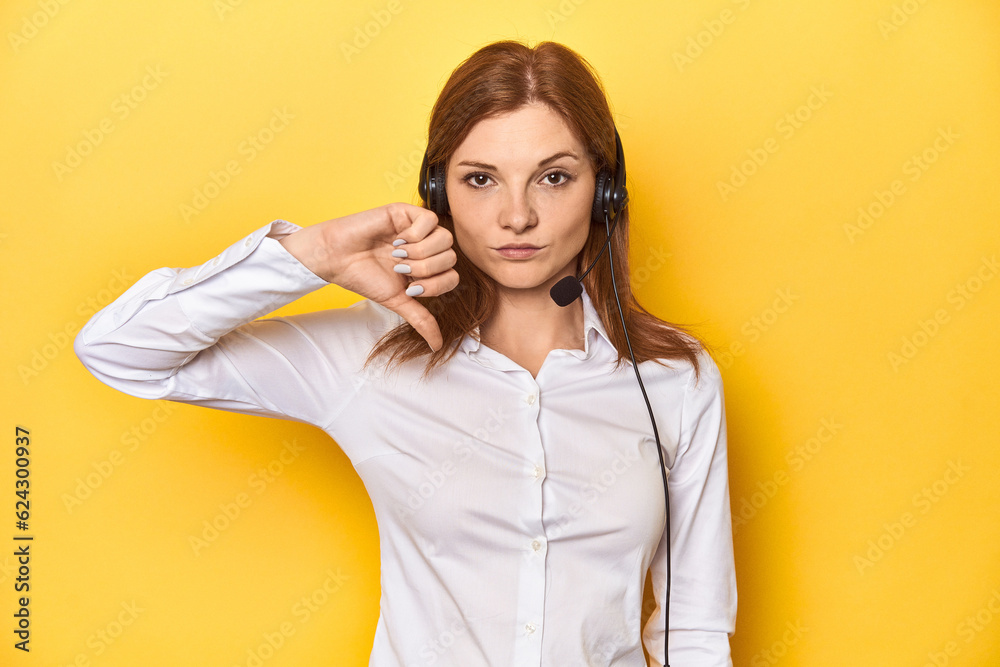 Obraz premium Call center redhead in white shirt, headphones on showing a dislike gesture, thumbs down. Disagreement concept.