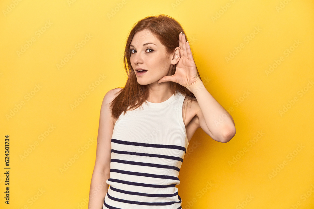 Redhead in a tank top, casual studio shot trying to listening a gossip. Redhead in a tank top, casual studio shot trying to listening a gossip.