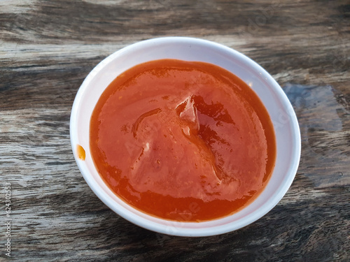 Tomato sauce served on a small plate. Placed on a wooden table.