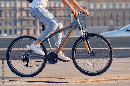 A young man rides a bicycle around the city, close-up.