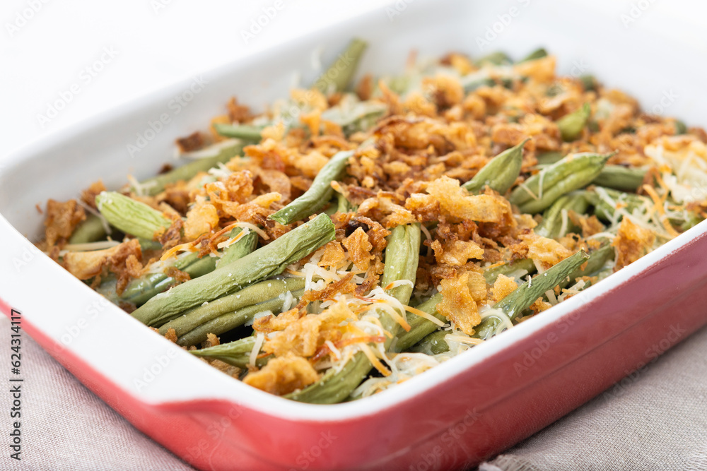 A traditional green bean casserole topped with French Fried Onions and cream of mushroom isolated on white background. Close up A traditional green bean casserole topped with French Fried Onions and cream of mushroom isolated on white background. Close up