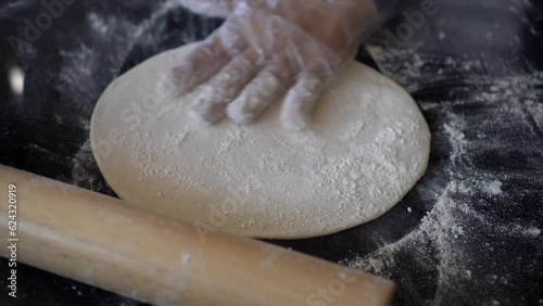 Italian chef preparing pizza dough and rolling on stone table strat flatten kneaded bread photo