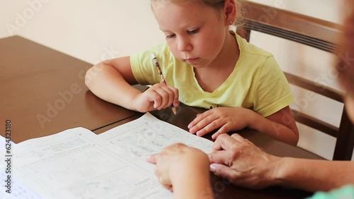 Little girl sitting at the table duing home work with grandmother back to school happy child photo