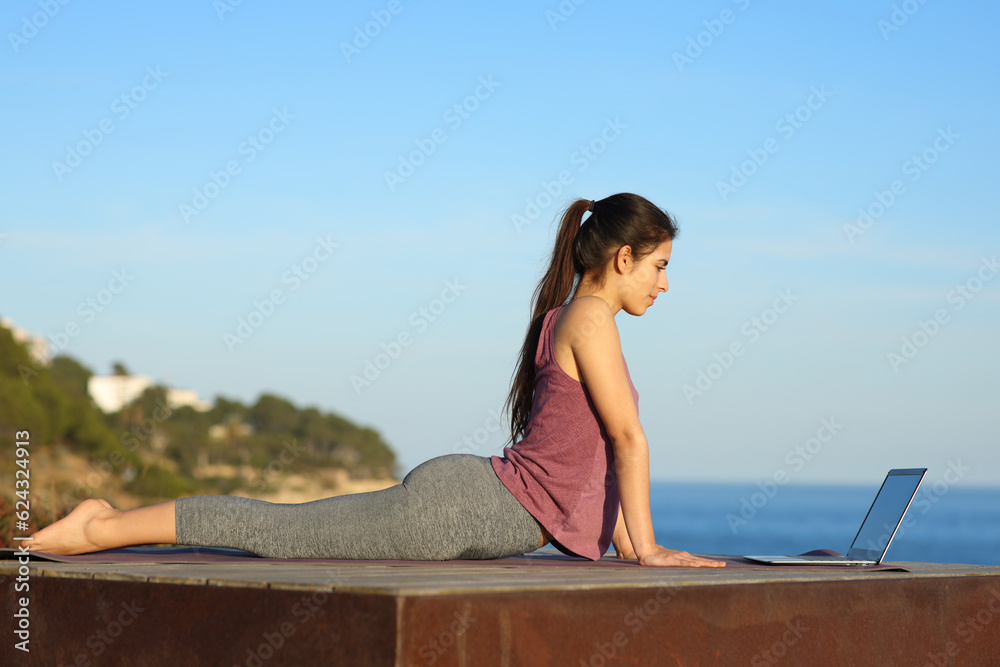 Woman e-learning yoga on the beach