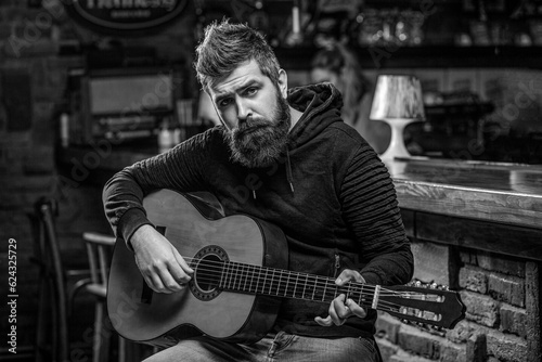 Bearded guitarist plays. Play guitar. Beard hipster man sitting in a pub. Live music. Black and white