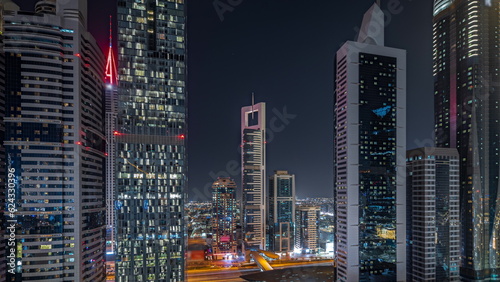 Panorama showing aerial view of Dubai International Financial District with many skyscrapers night timelapse.