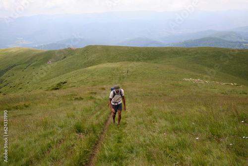 Mountain trekker: Tourist hiking high in the mountains.Man traveler with backpack is hiking in mountain.Traveling in nature. Baiului Mountains trails. Carpathians mountains in Romania. 