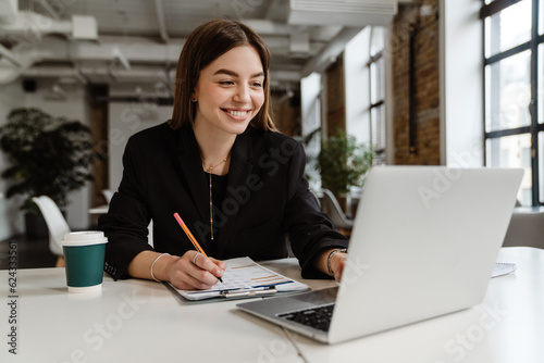 Cheerful business woman working on laptop in office