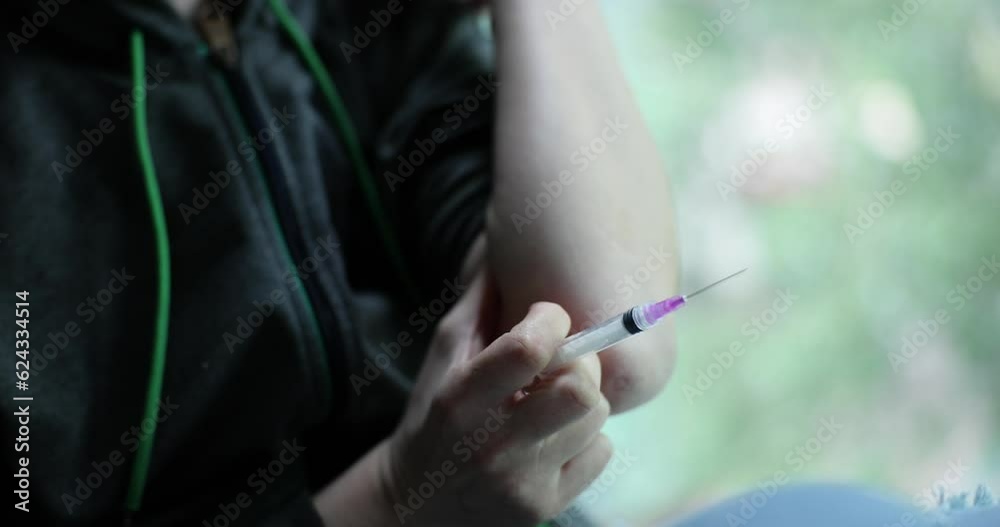 Person makes vaccination holding medical syringe in hand on blurred background. Concept of home health care with tool and drug addict slow motion