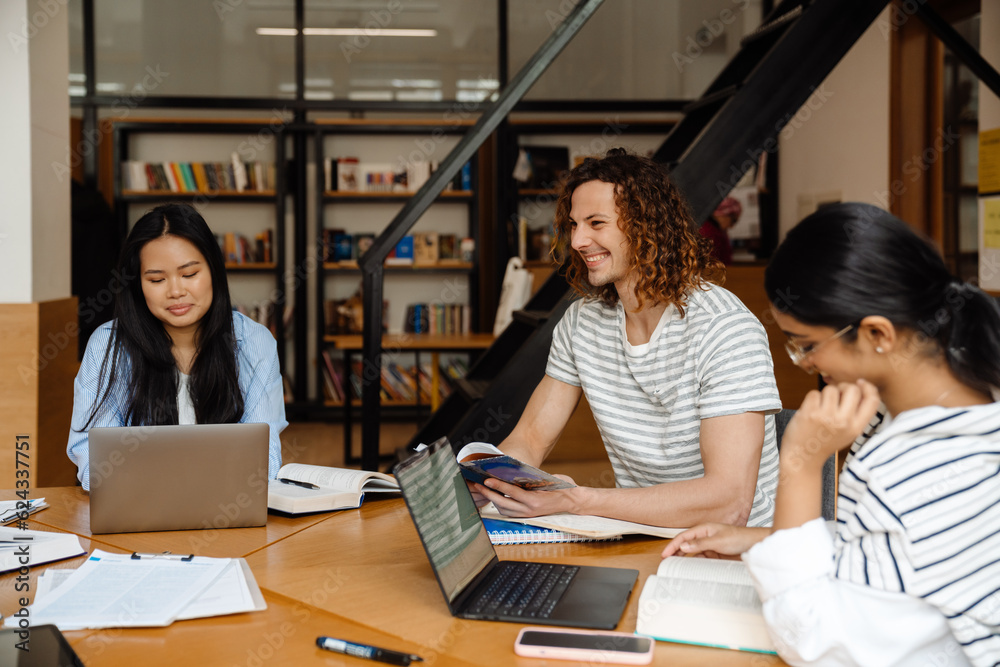 Group of students preparing for exams together while sitting at table in library