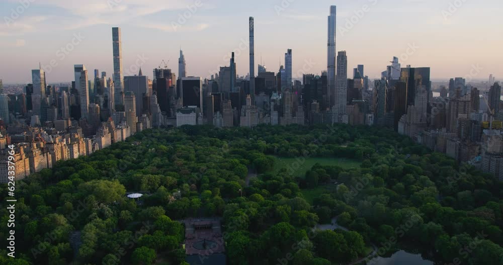 Helicopter Tour of New York City Architecture. Fly-By Over Central Park Towards a Panoramic View of Office Buildings and Skyscrapers of Manhattan in a Warm Evening Sunlight