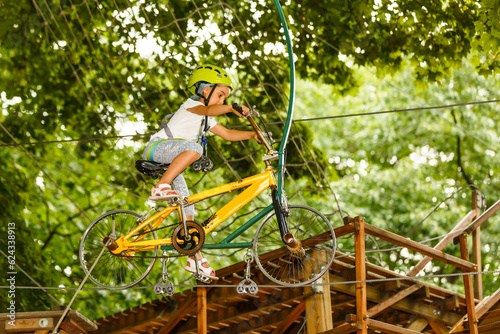 Adorable little girl enjoying her time in climbing adventure park on warm and sunny summer day