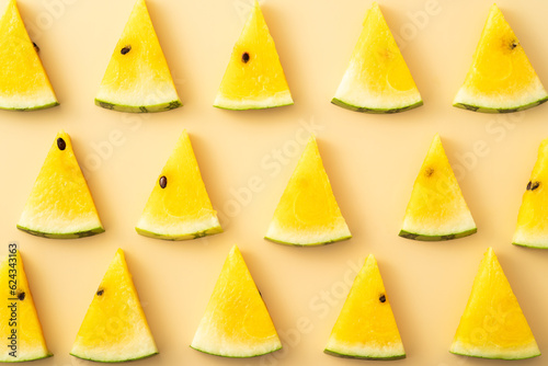 Sliced yellow watermelon pattern flat lay on pastel yellow table background.