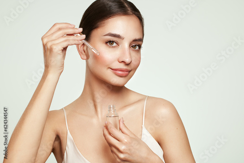 Canvas Print Young beautiful woman applying face serum with pipette