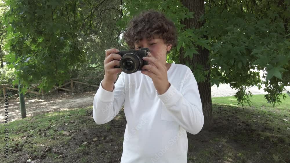 Boy kid 9 years old taking pictures photos with camera in a park during the holidays - travelling and learn to take pictures in childhood Boy kid 9 years old taking pictures photos with camera in a park during the holidays - travelling and learn to take pictures in childhood
