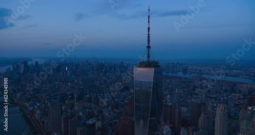 Late Evening Aerial Footage of a Camera Locked on Top of the One World Trade Center Skyscraper with Antenna. Helicopter Flying Around the Glass Building with a View on All Five New York City Boroughs