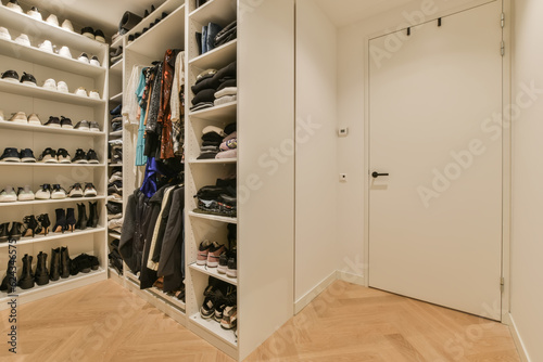 a walk - in closet with wooden flooring and white shelves filled with various pairs of shoes, handbags and bags © Casa imágenes