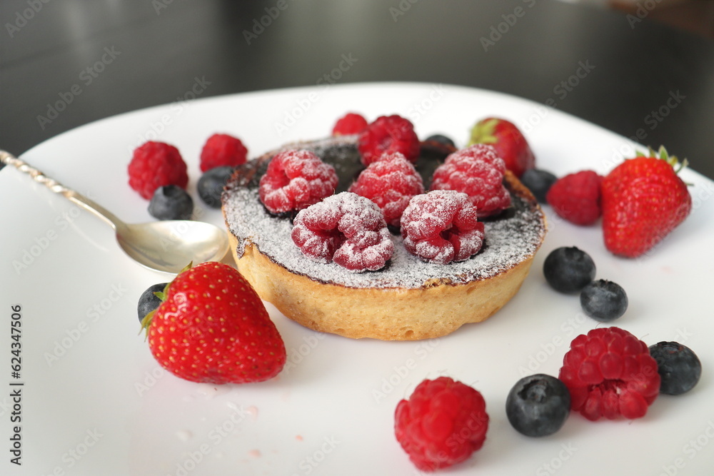 cream cake with raspberries and blueberries and small macaroons served on a large white plate cream cake with raspberries and blueberries and small macaroons served on a large white plate