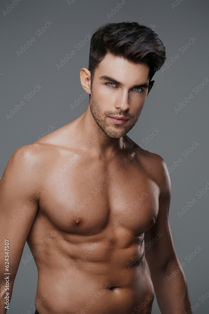 Charismatic close-up of a shirtless brunette model with a fit and toned physique against a modern gray backdrop Charismatic close-up of a shirtless brunette model with a fit and toned physique against a modern gray backdrop