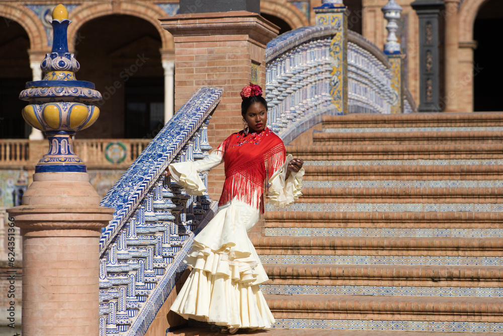 Young black woman dancing flamenco in a square in Seville, Spain. She wears a beige dress with ruffles and dances flamenco with a lot of art. Flamenco cultural heritage of humanity. Dance concept.