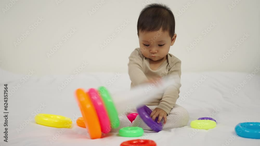 infant baby playing the pyramid toy with colored rings on a bed infant baby playing the pyramid toy with colored rings on a bed
