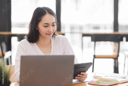 Young asian woman using laptop computer for business studying, watch online virtual webinar training meeting, video call. Focused asian woman or Latin business woman work in office, copy space. 