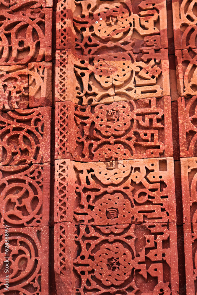 Close-up of Qutb Minar fresco and motifs on tower wall. Wall Detail from Qutub Minar monument in Delhi, India or Ancient carved red sandstone background at the Qutb Minar medieval monuments