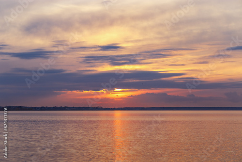 Aesthetic sky background on sunset, orange blue clouds and surface water. Nature abstract scenic summer lake with reflections on water, color gradient cloudscape, beauty nature, sunset on lake © yrabota