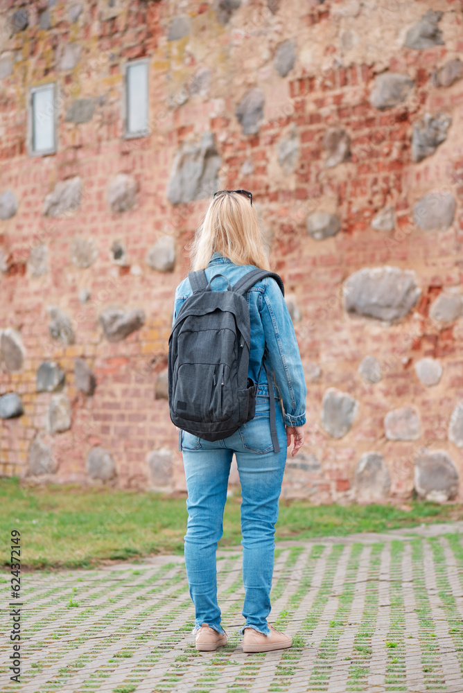 Young female traveler in denim clothes with backpack.