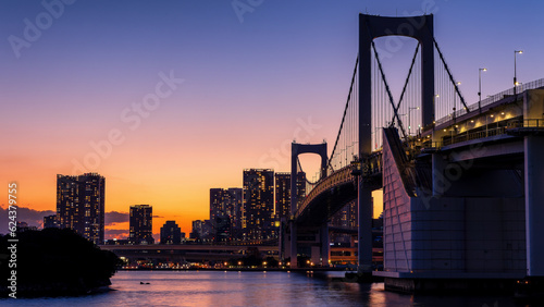 Purple and orange sky during sunset behind the skyscrapers of Tokyo and the Rainbow Bridge in Tokyo Bay