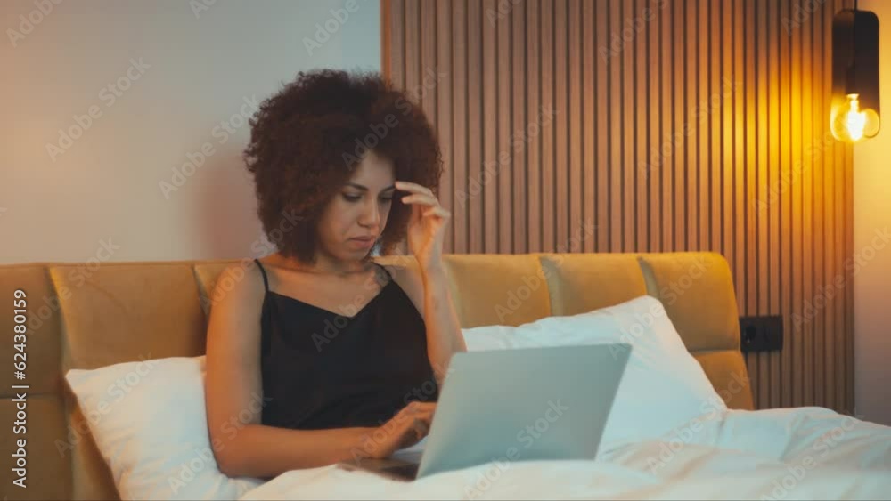 Concentrated African American woman freelancer typing on laptop in bed, deadline Concentrated African American woman freelancer typing on laptop in bed, deadline