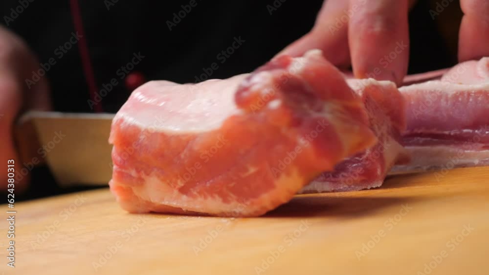 Divides raw pork ribs with a knife on a wooden board. Cutting pork ribs. Preparation food concept Divides raw pork ribs with a knife on a wooden board. Cutting pork ribs. Preparation food concept