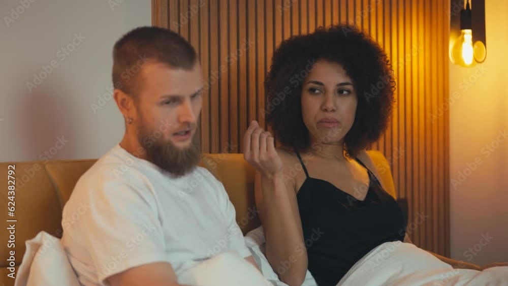 Young unhappy interracial couple fighting while lying bed, divorce risk, problem Young unhappy interracial couple fighting while lying bed, divorce risk, problem