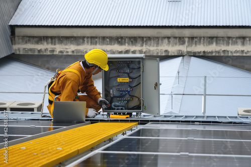 Wallpaper Mural Technician Young Wearing Safety Protective Clothing and Safety Belt to Checking Wiring in Control Panel by using Power Meter Tool with Details on Laptop in Installation Work of the Solar Panel. Torontodigital.ca