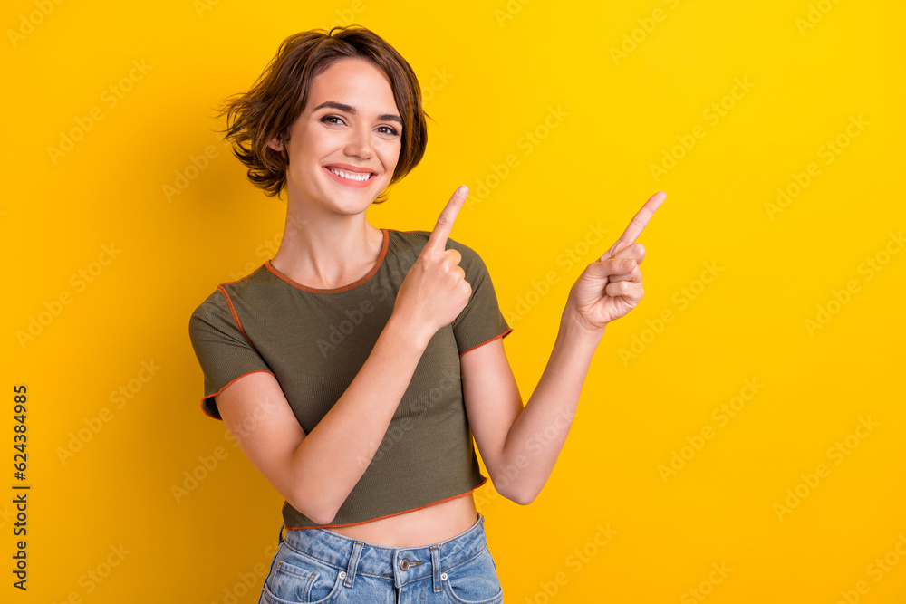 Photo of nice satisfied woman with bob hairstyle wear trendy t-shirt indicating at sale empty space isolated on yellow color background Photo of nice satisfied woman with bob hairstyle wear trendy t-shirt indicating at sale empty space isolated on yellow color background