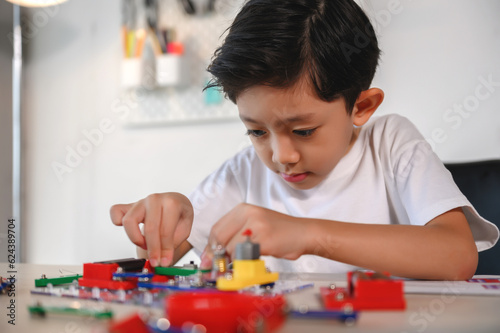 Asian Young Child Concentrate and Focus on Connecting Electronic Constructor. Learning and Experimentation with Circuit Board at Home. Develop the Brain, Practice Inventing for Future Innovators.