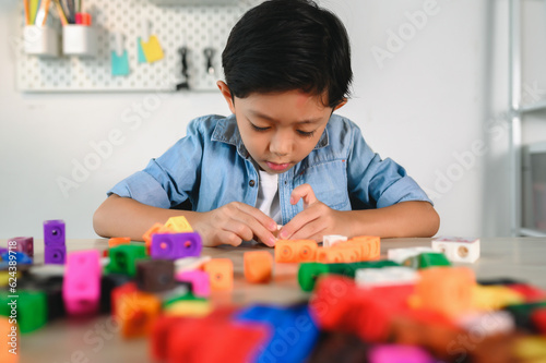 Asian Young Child Playing Colorful Plastic Cubes on Desk at Home. Learning and Education on Counting Cube in Math, Develop the Brain and Meditation while Playing.