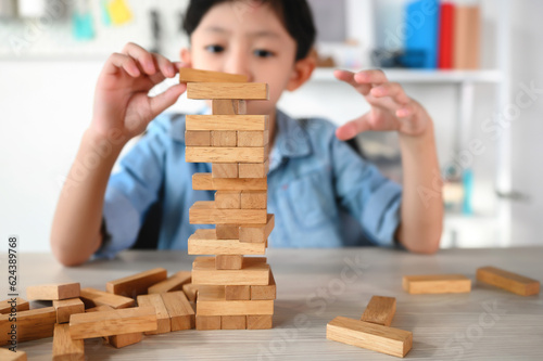 Child Boy Playing Jenga Game Exciting on Desk at Home. Careful and Attentive Keeping, Concentrate and Slowly Observing and Manage to Take It Out while Playing to Maintain Balance Objects.
