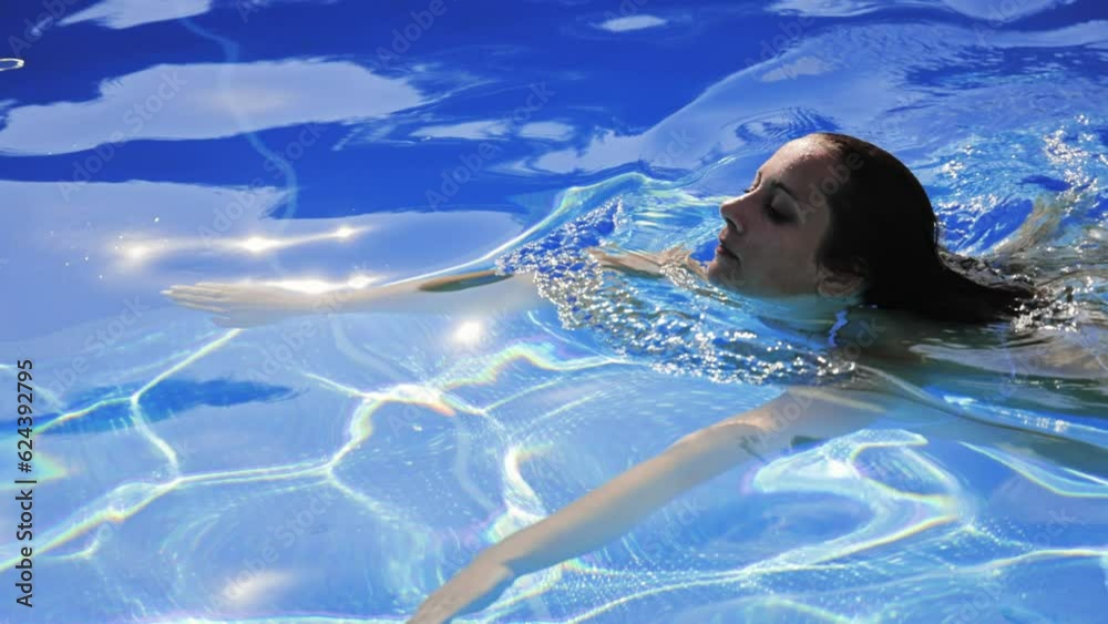 Beautiful girl swimming in a pool - extreme slow motion shot