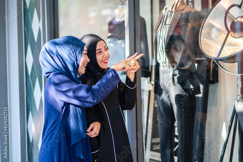 Two young asian fashion muslim woman enjoying shopping time summer sale walk and having fun talking together to buy something in the shop at fashion store