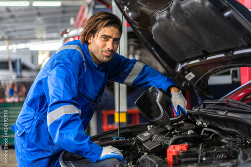 Professional car technician mechanic man in uniform work fixing vehicle car engine and maintenance repairing checking under the car hood in auto service. Automobile service garage